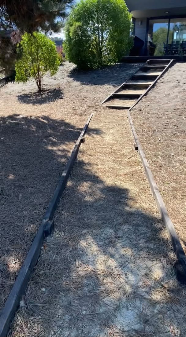 Sendero de maicillo con borde de madera y escalera hacia la terraza