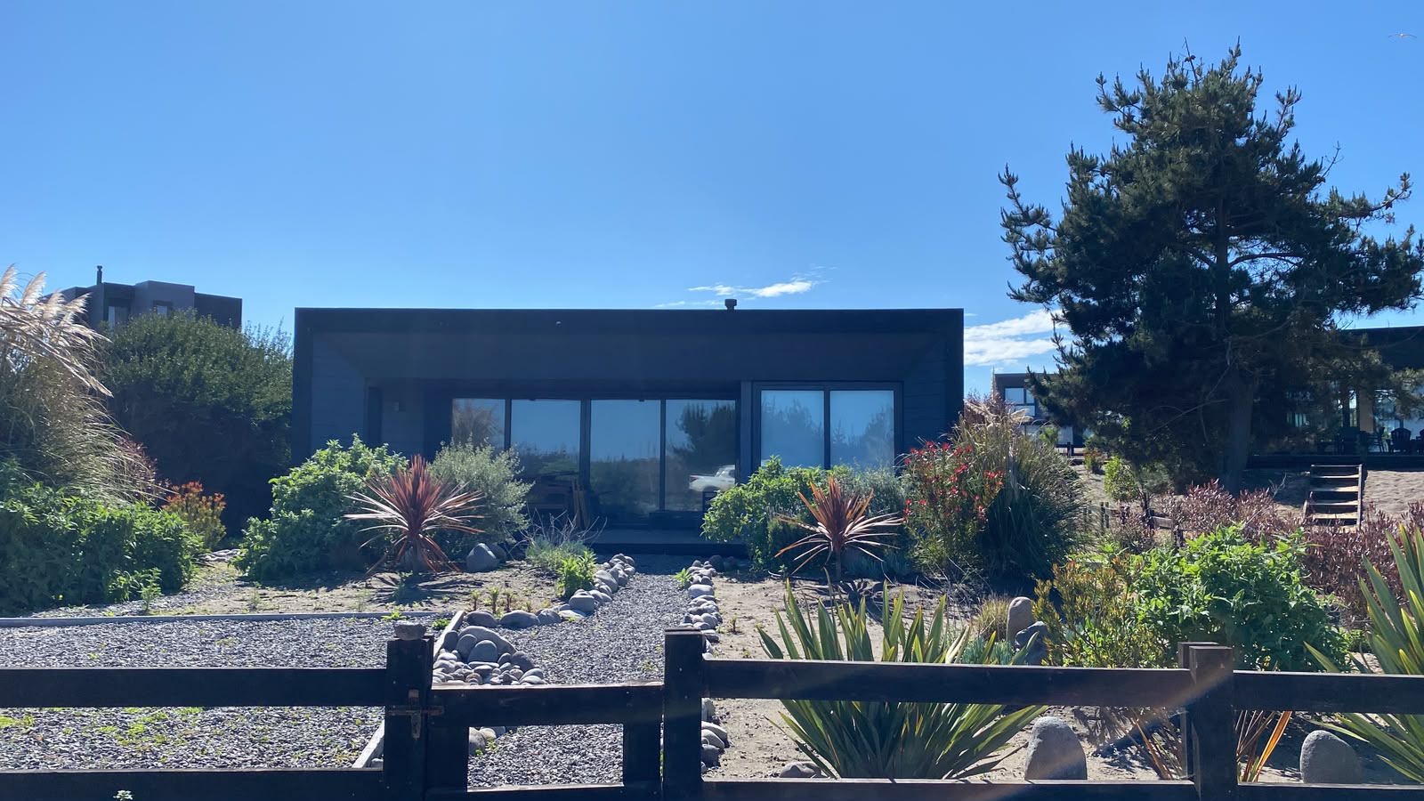 Jardín en arena con senderos de bolones y gravilla frente a la casa