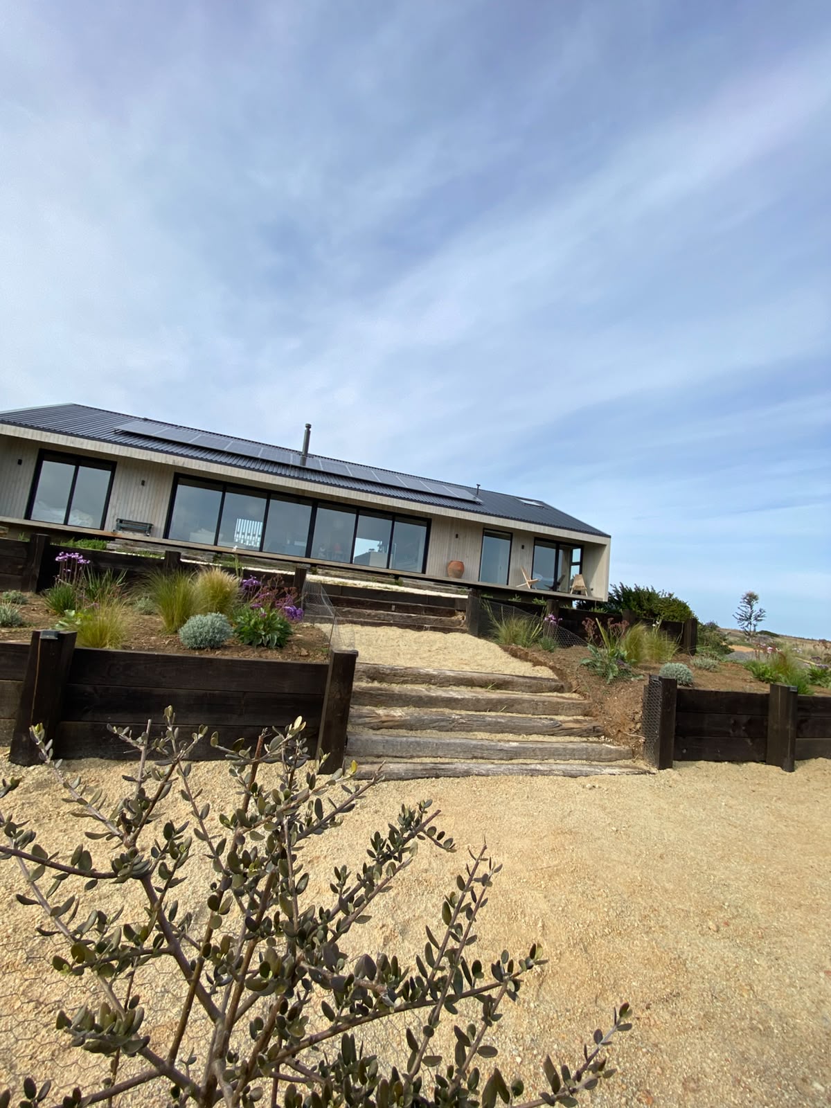 Casa moderna de Pichilemu con jardín en terrazas de durmientes y sendero de arena